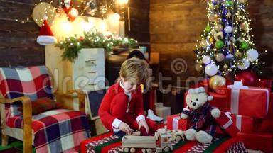 在木屋背景上带圣诞礼物的孩子。 <strong>快乐</strong>可爱的孩子打开圣诞礼物。 <strong>祝你快乐</strong>